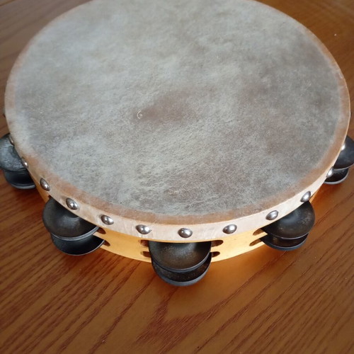 Tambourine used with natural skin, wooden frame, and metal jingles