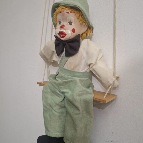 Porcelain clown doll on wooden swing, vintage collectible