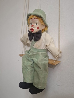 Porcelain clown doll on wooden swing, vintage collectible