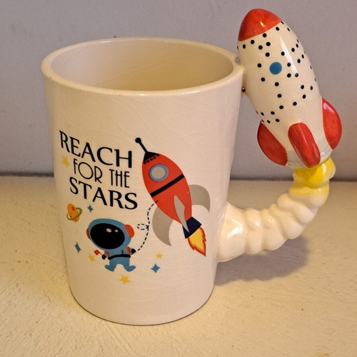 Ceramic space-themed mug with 3D rocket handle and Reach for the Stars phrase