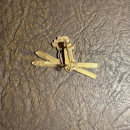 Vintage metal ski pin with crossed skis and flame