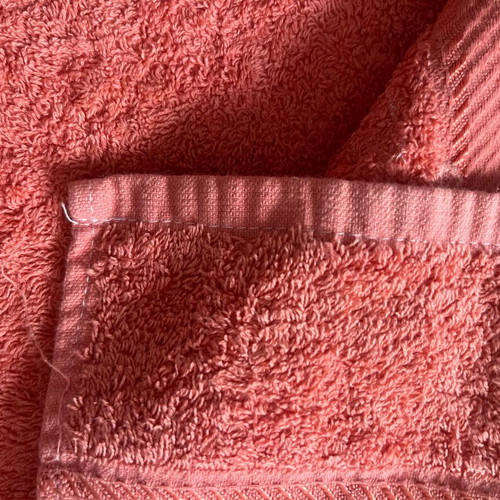 Face towel used, coral color with appliqué design