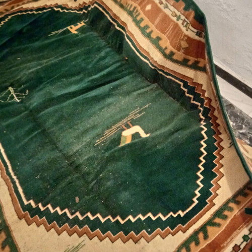 Turquoise machine-made rug used with animal and human designs
