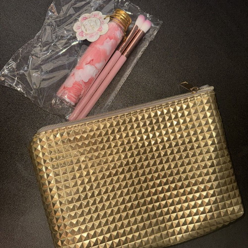 Gold makeup bag with two unused brushes