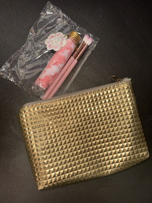 Gold makeup bag with two unused brushes
