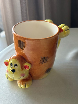 Vintage ceramic mug with embossed monkey design, used