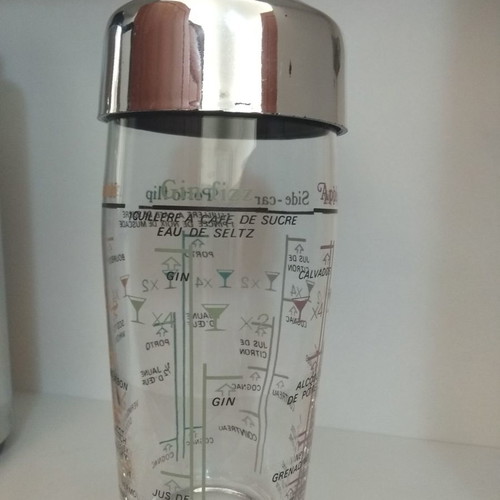 Acrylic shaker unused with strainer, measuring scale, and stainless lid