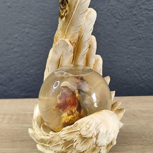Christmas decorative snow globe featuring the Nativity and a base shaped like an angel's wing
