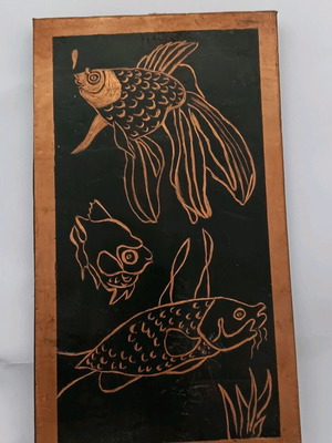 Copper artwork used with engraved fish on black background