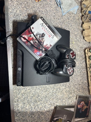 PlayStation 3 used with controller and Assassin's Creed 2 game