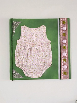 Handmade canvas frame with baby romper, pink flowers, beads, and lace