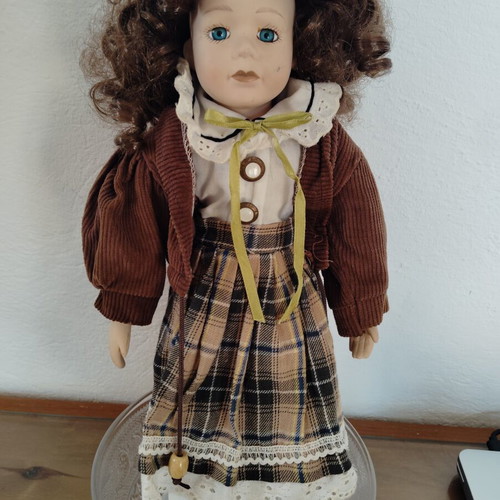 Porcelain doll like new with curly brown hair and fabric clothes