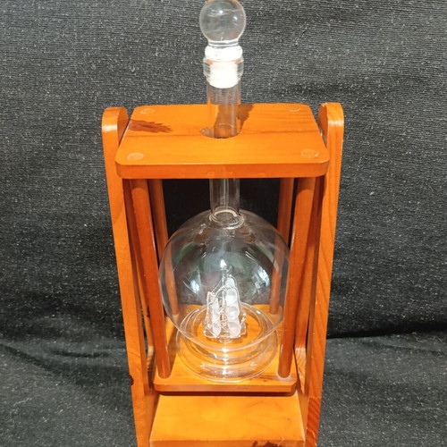 Vintage glass decanter with ship inside on wooden base, used