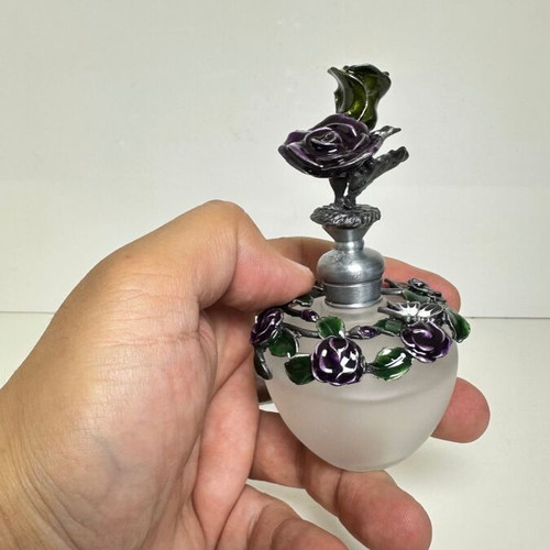 Vintage ornate perfume bottle with frosted glass and metal floral decoration