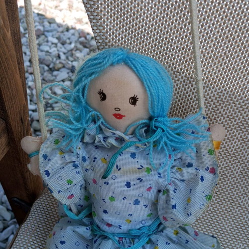 Cloth doll used, hanging in a swing