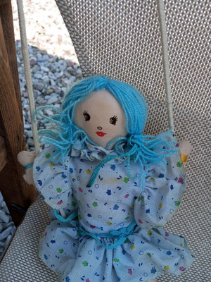Cloth doll used, hanging in a swing