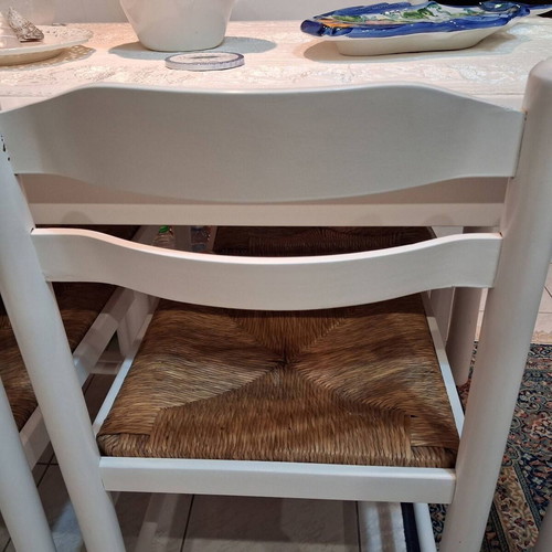 White wooden dining set used with 4 chairs with cane seats