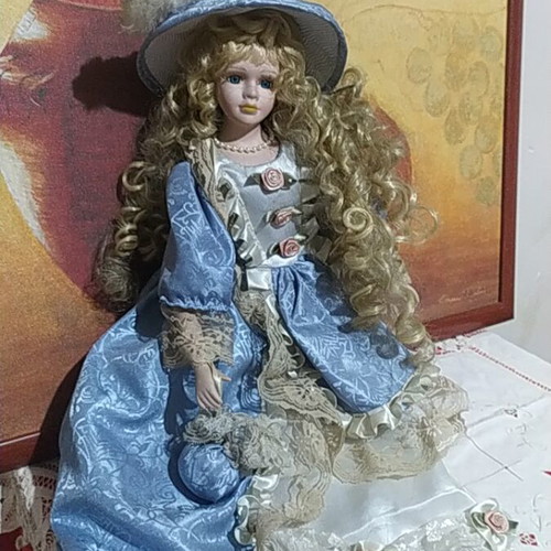 Porcelain Victorian-style doll with curly blonde hair and blue lace dress
