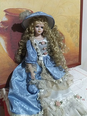 Porcelain Victorian-style doll with curly blonde hair and blue lace dress