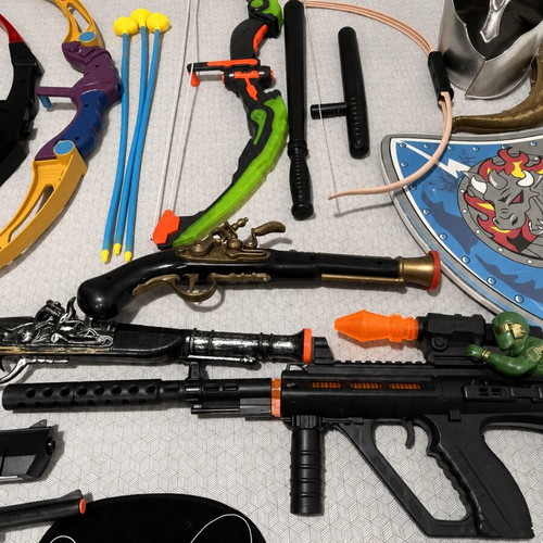 Children's toy weapons set including nerf guns, swords, bows, and truck race track