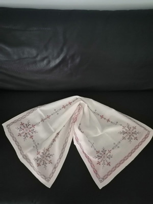Handmade embroidered table runner with geometric pattern on white linen