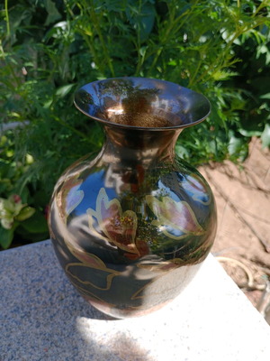 Intricately enameled brass vase with flowers.