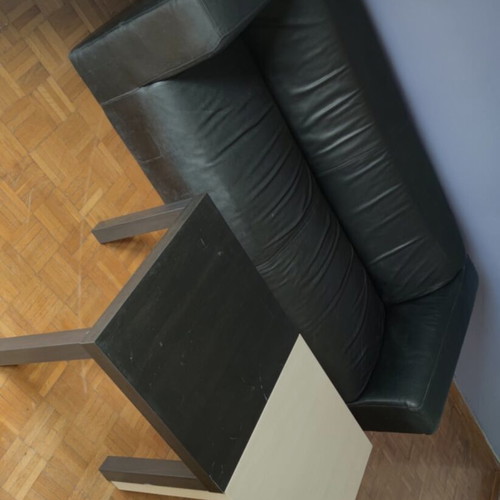 Black leather three-seater sofa used with coffee tables