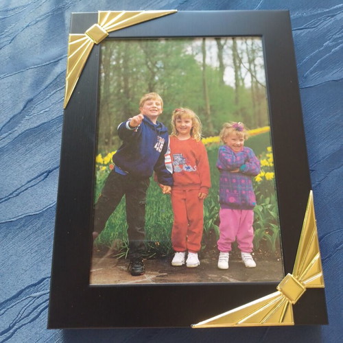 Black photo frame with golden decorative bows used