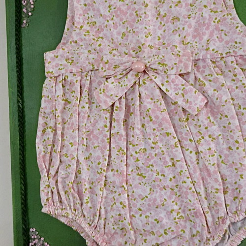Handmade canvas frame with baby romper, pink flowers, beads, and lace
