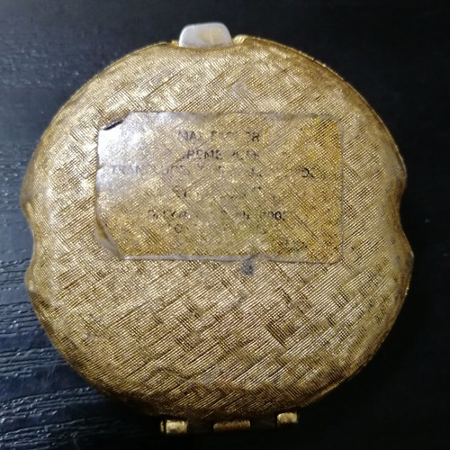 Vintage powder compact used with mirror and gold-plated box with emerald
