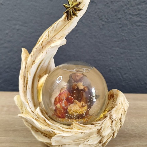 Christmas decorative snow globe featuring the Nativity and a base shaped like an angel's wing