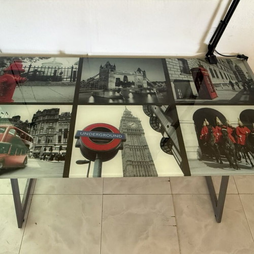 Desk with metal frame and glass surface featuring London images like new
