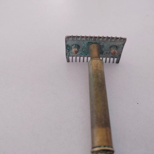 Vintage brass razor used with visible wear and oxidation
