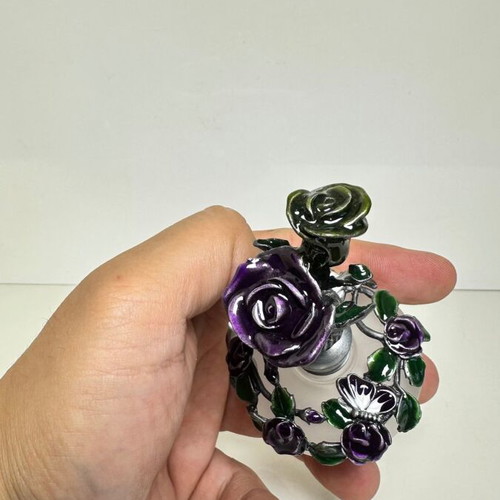 Vintage ornate perfume bottle with frosted glass and metal floral decoration