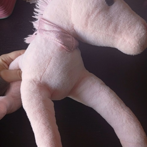 Pink plush unicorn toy used in lying position