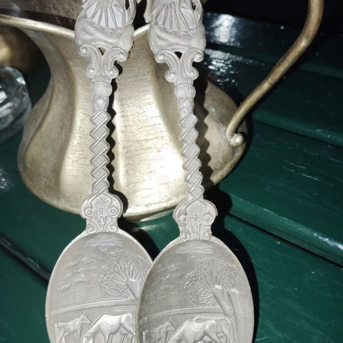 Two large decorative pewter spoons used with intricate animal designs