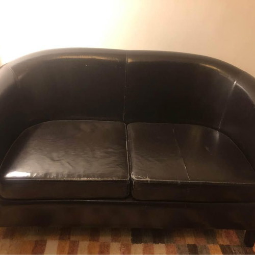 Two-seater black faux leather sofa used with some cushion wear