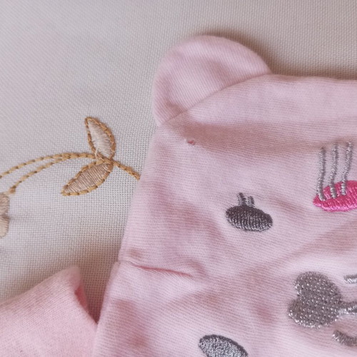 Two baby hats, one with a hole