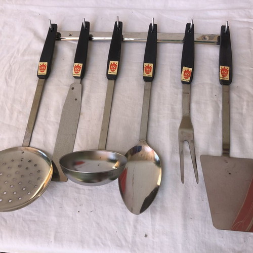 Vintage stainless steel kitchen tool set with black handles and wall rack