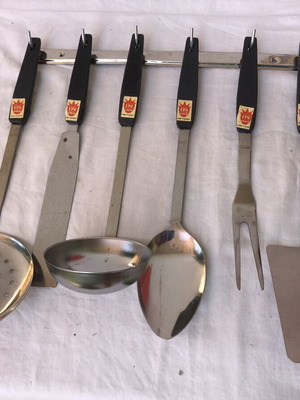 Vintage stainless steel kitchen tool set with black handles and wall rack