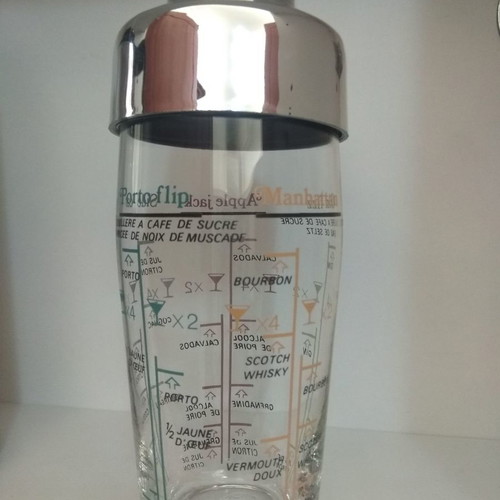 Acrylic shaker unused with strainer, measuring scale, and stainless lid