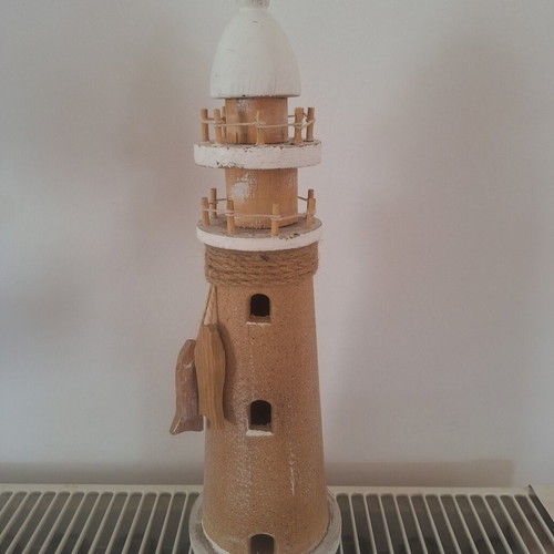 Decorative wooden sailboat with fabric sails and wooden lighthouse used