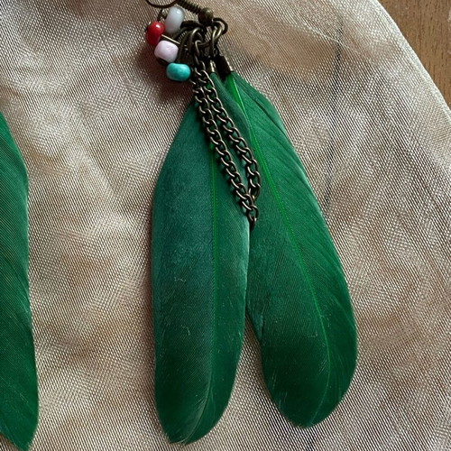 Handmade earrings used with green feathers and multicolored beads