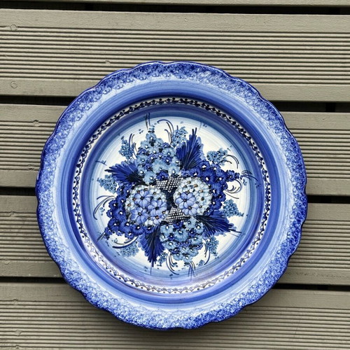 Handmade ceramic wall plate used with blue floral motif