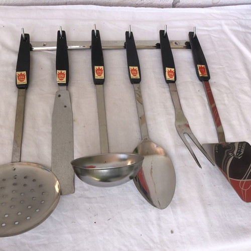 Vintage stainless steel kitchen tool set with black handles and wall rack
