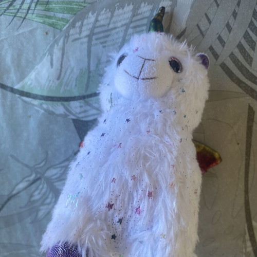 Unicorn plush toy with colorful shiny wings and metallic purple details