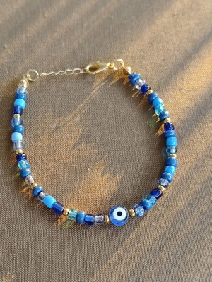 Blue bracelet with gold details and eye charm