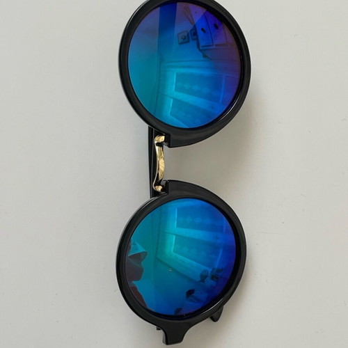 Sunglasses with round iridescent lens used, black frame with gold detail