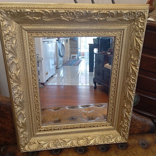 Baroque wall mirror with carved gold frame and embossed motifs