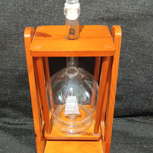 Vintage glass decanter with ship inside on wooden base, used